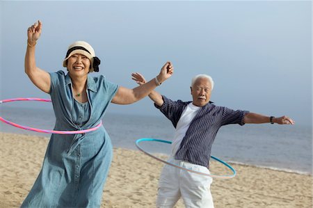 Couple with hula hoops on beach Stock Photo - Premium Royalty-Free, Code: 693-06013734