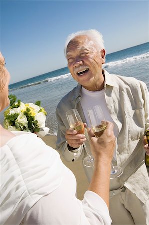 senior couple holding wedding photo - Senior newly weds toasting champagne at beach Stock Photo - Premium Royalty-Free, Code: 693-06013798