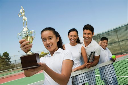 Tennis Family on court by net, daughter holding trophy, portrait Stock Photo - Premium Royalty-Free, Code: 693-06013820