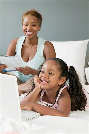 Mother and Daughter on bed Looking at Laptop Stock Photo - Premium Royalty-Free, Code: 693-06013924