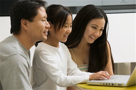 Daughter using laptop with mother and father in living room Foto de stock - Sin royalties Premium, Código: 693-06013937
