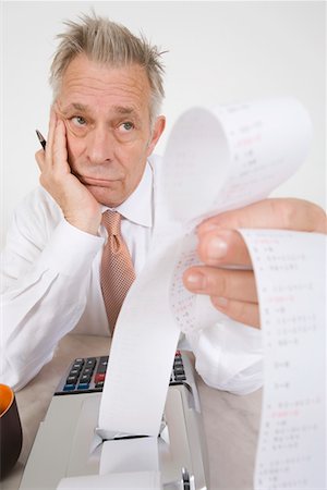 Businessman Looking at Calculator Paper Foto de stock - Sin royalties Premium, Código: 693-06020045