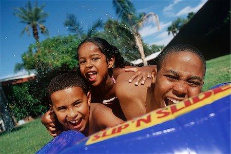 Two boys (7-9) and girl (5-6) playing in wading pool Stock Photo - Premium Royalty-Free, Code: 693-06020090