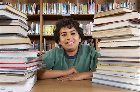 simsearch:640-05761270,k - School boy sitting at desk with books in library, portrait Stock Photo - Premium Royalty-Free, Code: 693-06020476