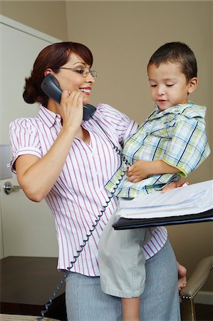 Business woman using phone with son at home Stock Photo - Premium Royalty-Free, Code: 693-06020491