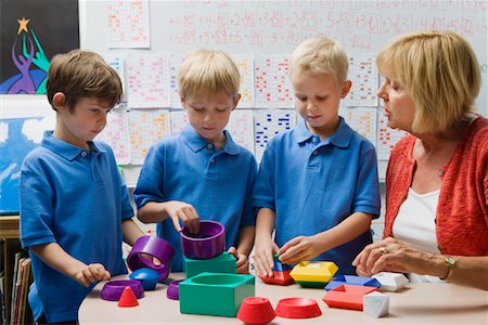 simsearch:693-06020640,k - Teacher Helping Little Boys Assemble Educational Puzzle Toys Foto de stock - Sin royalties Premium, Código: 693-06020562