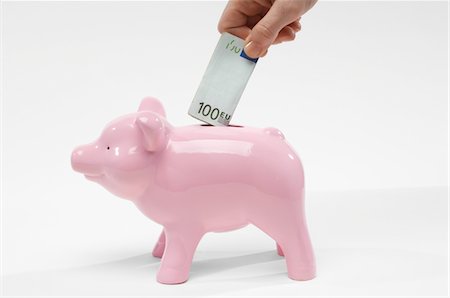 Hand Putting Money in Piggy Bank Stock Photo - Premium Royalty-Free, Code: 693-06021336