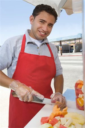 Portrait of male street vendor chopping fruit Stock Photo - Premium Royalty-Free, Code: 693-06021527