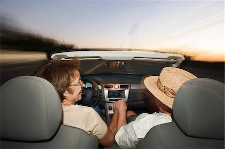 Senior couple driving in convertible on country road at dusk, back view Stock Photo - Premium Royalty-Free, Code: 693-06021677