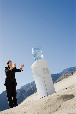 durstig - Homme d'affaires permanent de refroidisseur d'eau dans le désert Photographie de stock - Premium Libres de Droits, Code: 693-06021764