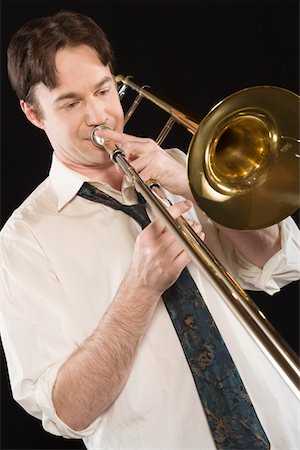 people playing brass instruments - Mid-adult man with open-collar shirt plays the trombone Stock Photo - Premium Royalty-Free, Code: 693-06021862