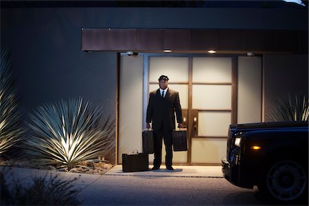 doorman full length - Chauffeur stands at lit entrance doorway with luggage Stock Photo - Premium Royalty-Free, Code: 693-06022174