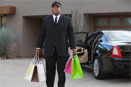 shopping spree - Chauffeur holds shopping bags in driveway near luxury vehicle Stock Photo - Premium Royalty-Free, Code: 693-06022171