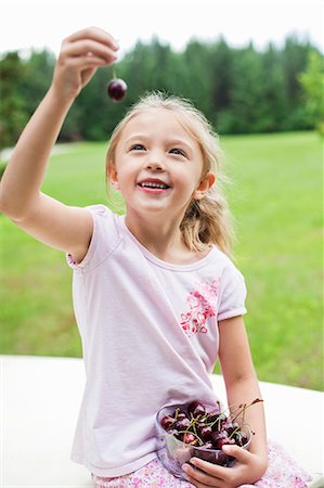 Happy young girl holding bowl full of bing cherries in park Foto de stock - Royalty Free Premium, Número: 693-06120673