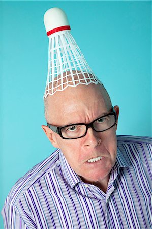 Portrait of angry senior man with shuttlecock on head over colored background Fotografie stock - Premium Royalty-Free, Codice: 693-06120721