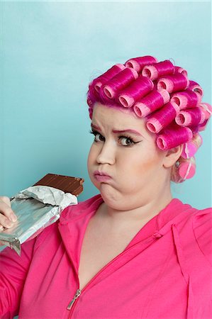 fat woman and one person - Portrait of a young woman making faces while holding chocolate bar over colored background Stock Photo - Premium Royalty-Free, Code: 693-06120738