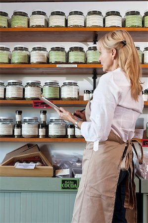 saleswoman blond - Side view of senior female employee going through list of spices in store Stock Photo - Premium Royalty-Free, Code: 693-06120765