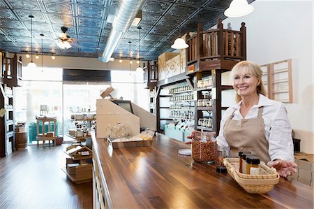 dueña - Happy senior female spice merchant standing at counter while looking away in store Foto de stock - Sin royalties Premium, Código: 693-06120769