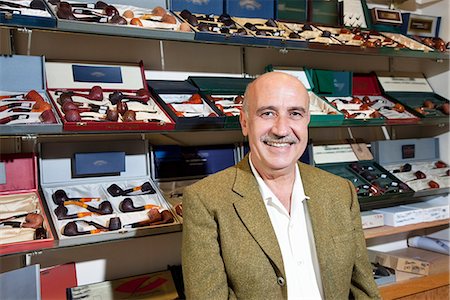 Portrait of tobacco shop owner with pipes in background Stock Photo - Premium Royalty-Free, Code: 693-06120794