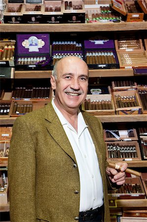 Portrait of a male owner of tobacco shop standing with cigar boxes in background Foto de stock - Sin royalties Premium, Código: 693-06120796