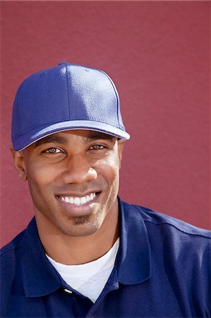 Portrait of a happy African American man with cap over colored background Stock Photo - Premium Royalty-Free, Code: 693-06120816