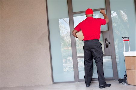 delivery african ethnicity - Rear view of a delivery man with packages knocking at door Stock Photo - Premium Royalty-Free, Code: 693-06120826