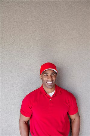 Portrait of a happy African American delivery man against wall Foto de stock - Sin royalties Premium, Código: 693-06120830