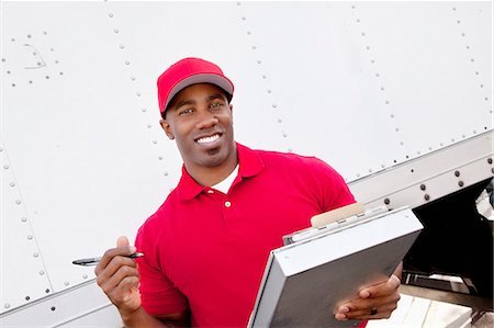 delivery african ethnicity - Portrait of a happy African American man holding clipboard with delivery truck in background Stock Photo - Premium Royalty-Free, Code: 693-06120831