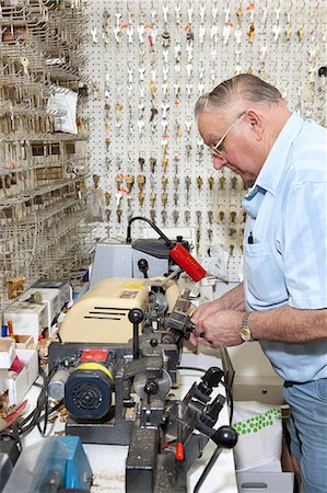 Side view of senior locksmith making key in store Foto de stock - Sin royalties Premium, Código: 693-06120841