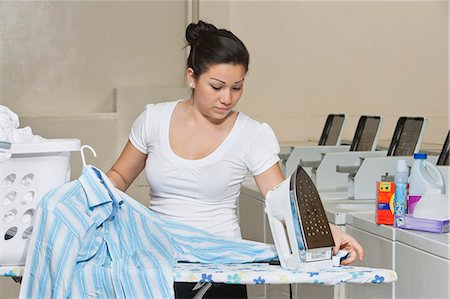 Young female employee ironing clothes in Laundromat Foto de stock - Sin royalties Premium, Código: 693-06120874