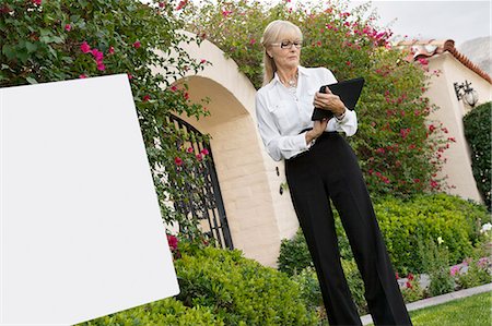 reading notice board - Senior female agent reading from clipboard Stock Photo - Premium Royalty-Free, Code: 693-06120908