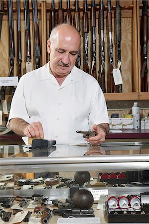 Mature male merchant at gun shop with credit card reader Fotografie stock - Premium Royalty-Free, Codice: 693-06120928