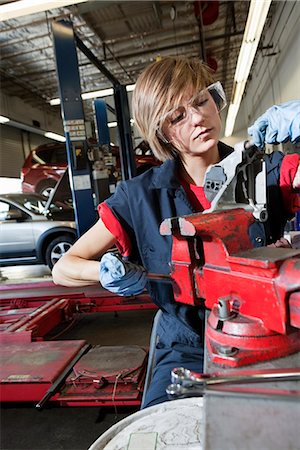 Young mechanic in protective clothing concentrating on repairing machine part in garage Stock Photo - Premium Royalty-Free, Code: 693-06120966