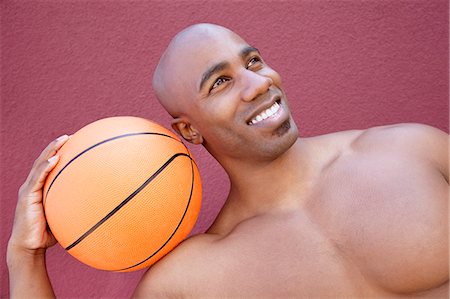 Young African American man with basketball on shoulder looking away over colored background Stock Photo - Premium Royalty-Free, Code: 693-06120987