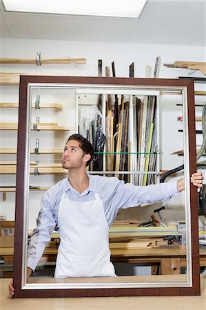 staff photo - Young craftsman looking on frame's corner in workshop Stock Photo - Premium Royalty-Free, Code: 693-06120997