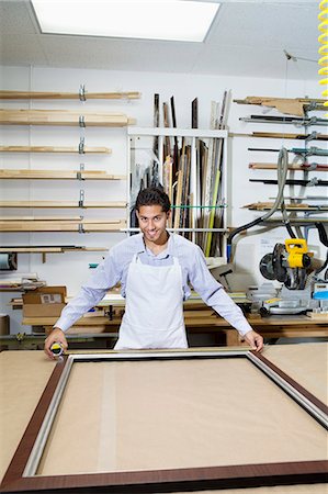 Portrait of a happy young employee measuring picture frame Stock Photo - Premium Royalty-Free, Code: 693-06120990