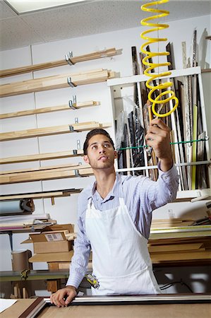 people spiral - Young craftsman holding equipment in frame workshop Stock Photo - Premium Royalty-Free, Code: 693-06121000