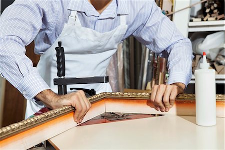 frame with hand - Midsection of a young craftsman working on picture frame's corner Stock Photo - Premium Royalty-Free, Code: 693-06121002