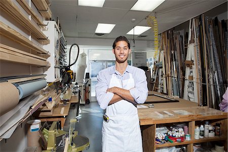 Portrait of a happy young craftsman standing with arms crossed in workshop Stock Photo - Premium Royalty-Free, Code: 693-06121011