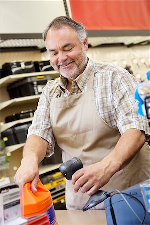 retail clerk - Happy mature store clerk using barcode reader at checkout counter Stock Photo - Premium Royalty-Free, Code: 693-06121046