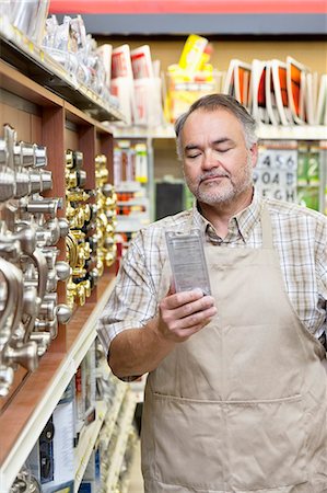 Mature salesperson reading instructions in hardware store Stock Photo - Premium Royalty-Free, Code: 693-06121054