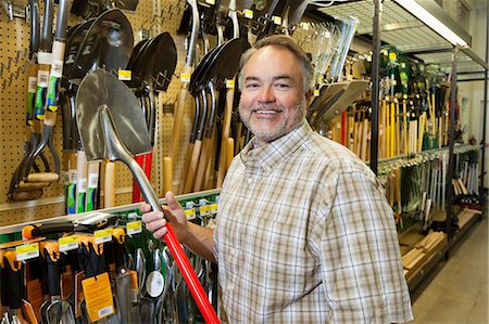 Portrait of a happy mature man holding shovel in hardware store Foto de stock - Sin royalties Premium, Código: 693-06121076