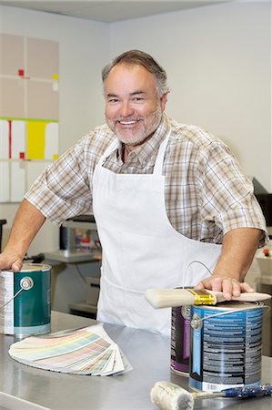 shopping counter - Portrait of a cheerful mature store clerk with paint cans and brush in hardware shop Stock Photo - Premium Royalty-Free, Code: 693-06121072