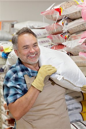 small business owner middle aged - Happy mature salesperson carrying sack in feed store Stock Photo - Premium Royalty-Free, Code: 693-06121155