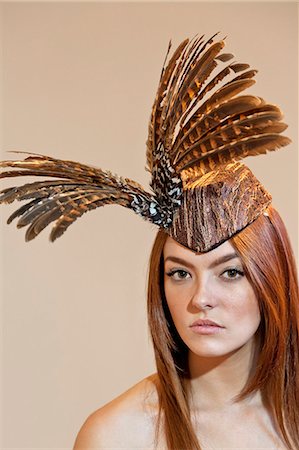 feathers studio - Portrait of a young woman wearing feathered headdress on colored background Foto de stock - Sin royalties Premium, Código: 693-06121188