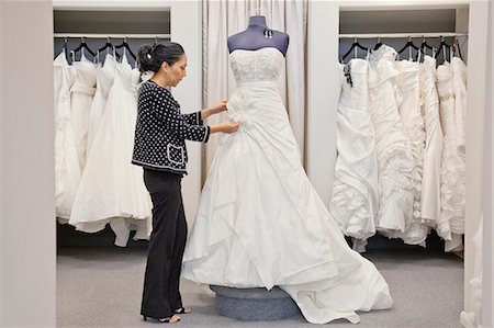 Side view of a mature employee adjusting elegant wedding dress in bridal store Foto de stock - Sin royalties Premium, Código: 693-06121245