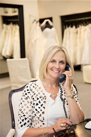 female indoor garments images - Portrait of a happy woman listening to telephone receiver in bridal store Stock Photo - Premium Royalty-Free, Code: 693-06121264