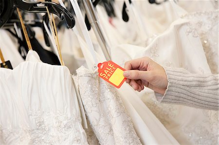 Cropped shot of female hands holding price tag attached to wedding gown in bridal boutique Foto de stock - Sin royalties Premium, Código: 693-06121268