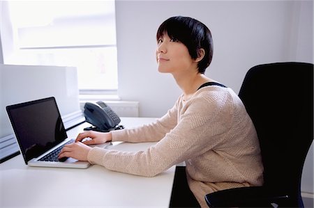 simsearch:693-03644020,k - Jeune femme asiatique utilisant un ordinateur portable tout en regardant loin Photographie de stock - Premium Libres de Droits, Code: 693-06121313