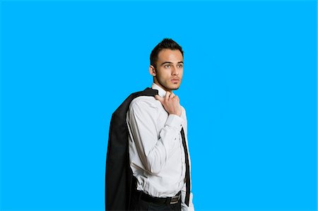 standing - Confident young businessman with suit over shoulder on colored background Stock Photo - Premium Royalty-Free, Code: 693-06121341